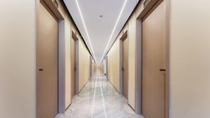Um corredor comprido e estreito com portas em ambos os lados, dando acesso a quartos individuais.