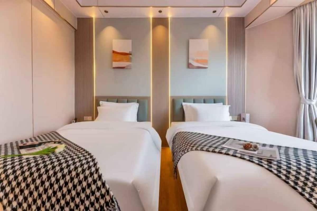 A hotel room with two beds, a large window, and a modern design.