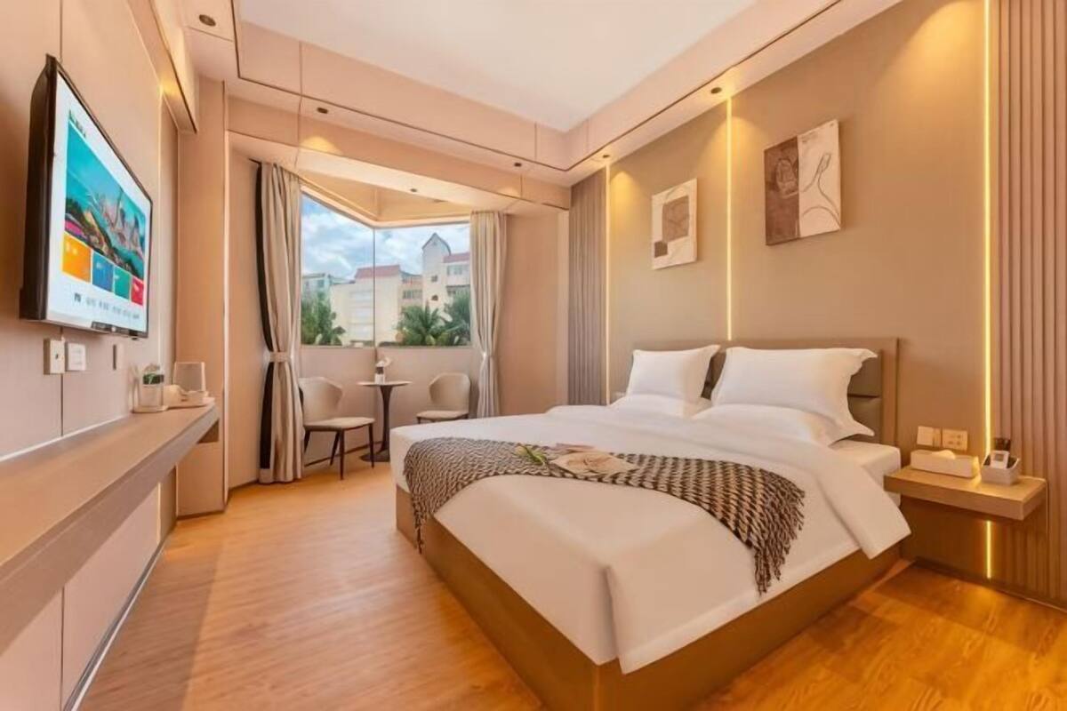 A hotel room with a large bed, a TV, a balcony with a view, and a small table.