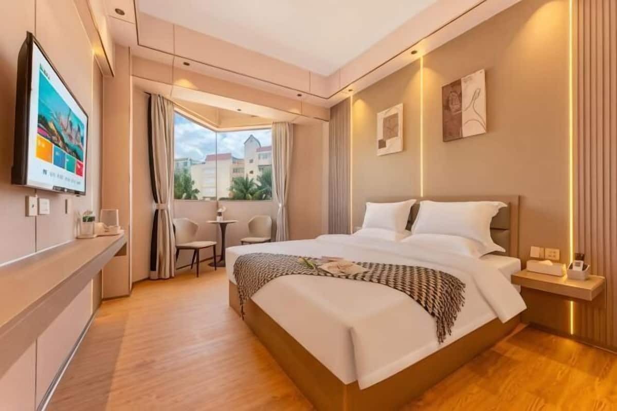 Habitación de hotel con una cama grande, televisión, balcón con vistas y una mesita.
