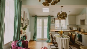 A cozy living room with a dining area, a kitchen, and a view of the outdoors.