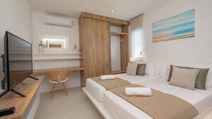Ett modernt hotellrum med en stor säng, ett skrivbord, en stol, en tv och en tavla på väggen.