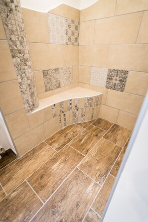 A shower area with a wooden floor and a shelf.