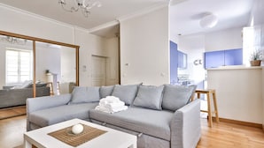 Moderni olohuone, jossa on harmaa kulmasohva, valkoinen sohvapöytä ja puulattia.