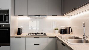 A modern kitchen with grey cabinets, a stainless steel sink, a coffee maker, and a kettle. - Celestial 3BR Apartment with Balcony (Palaio Faliro)
