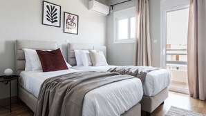 A modern bedroom with two beds, a nightstand, and a window with curtains. - Celestial 3BR Apartment with Balcony (Palaio Faliro)