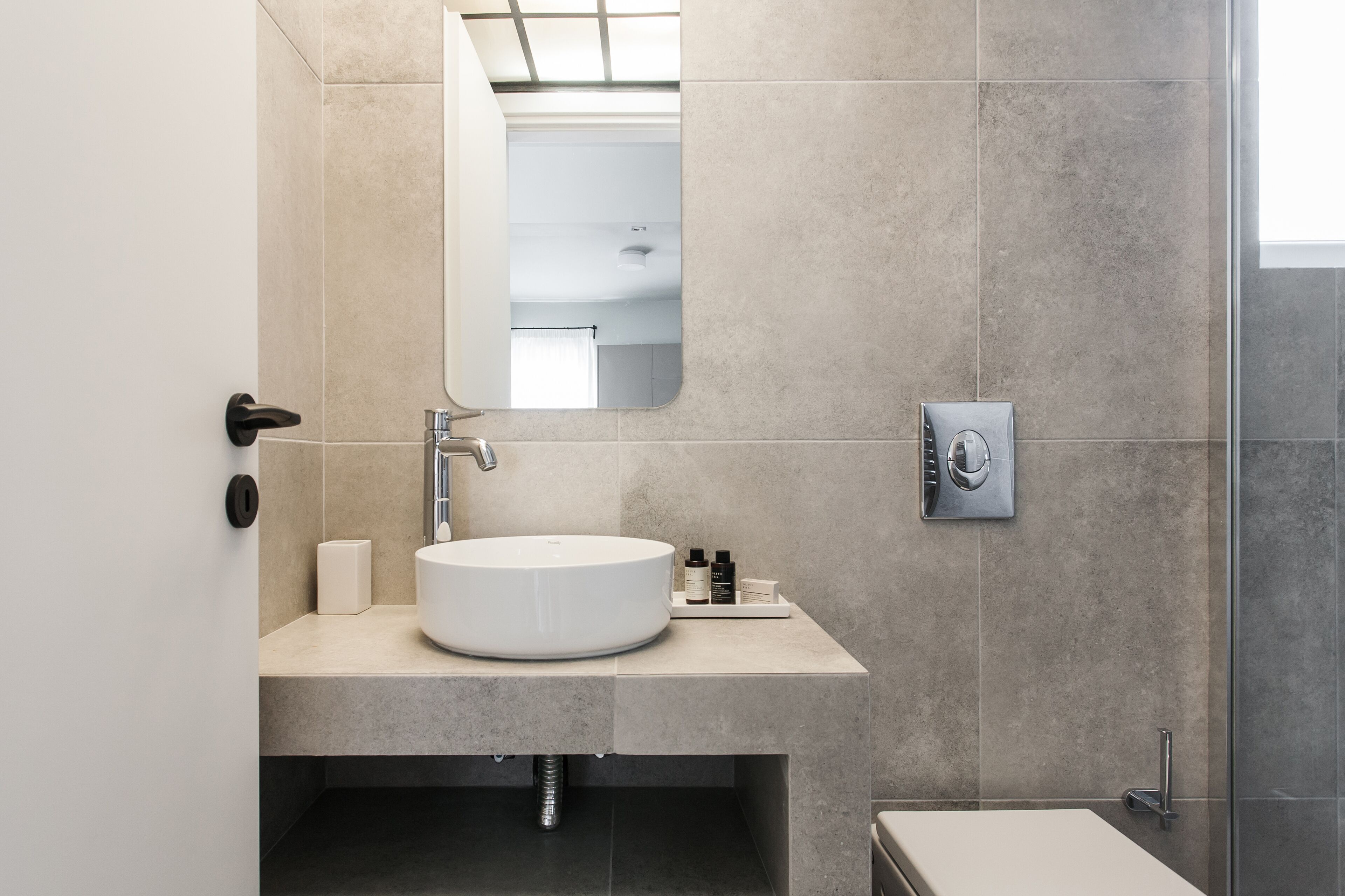 A modern bathroom with a round sink, a mirror, and a shower area.