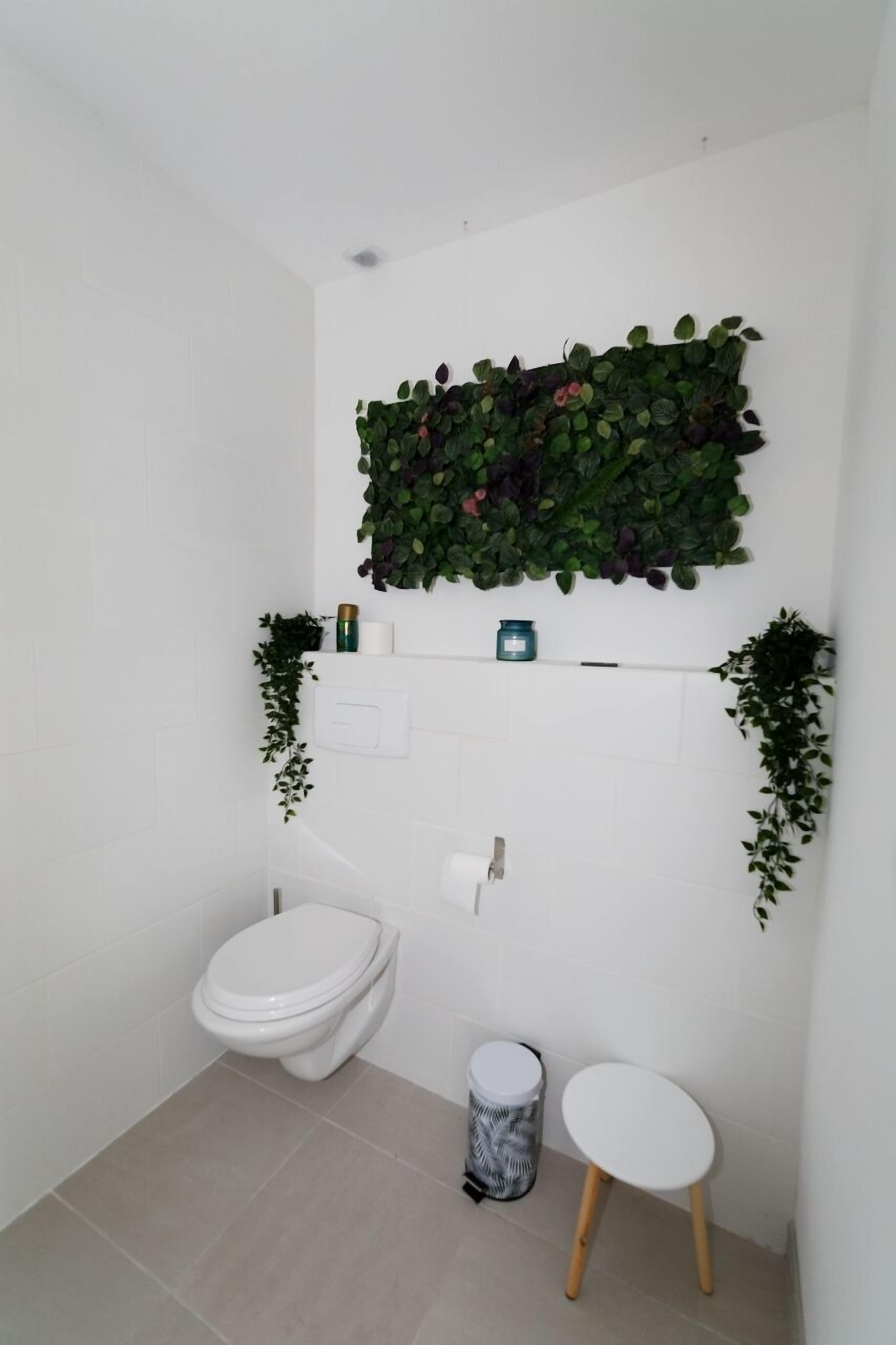 Un baño con inodoro, lavamanos y dos taburetes pequeños.