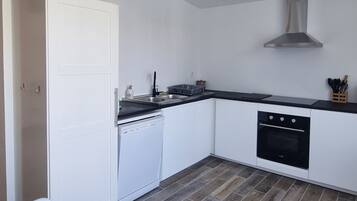 Eine moderne Küche mit weißen Schränken, einer schwarzen Arbeitsplatte, einem eingebauten Backofen und einer Edelstahl-Dunstabzugshaube.