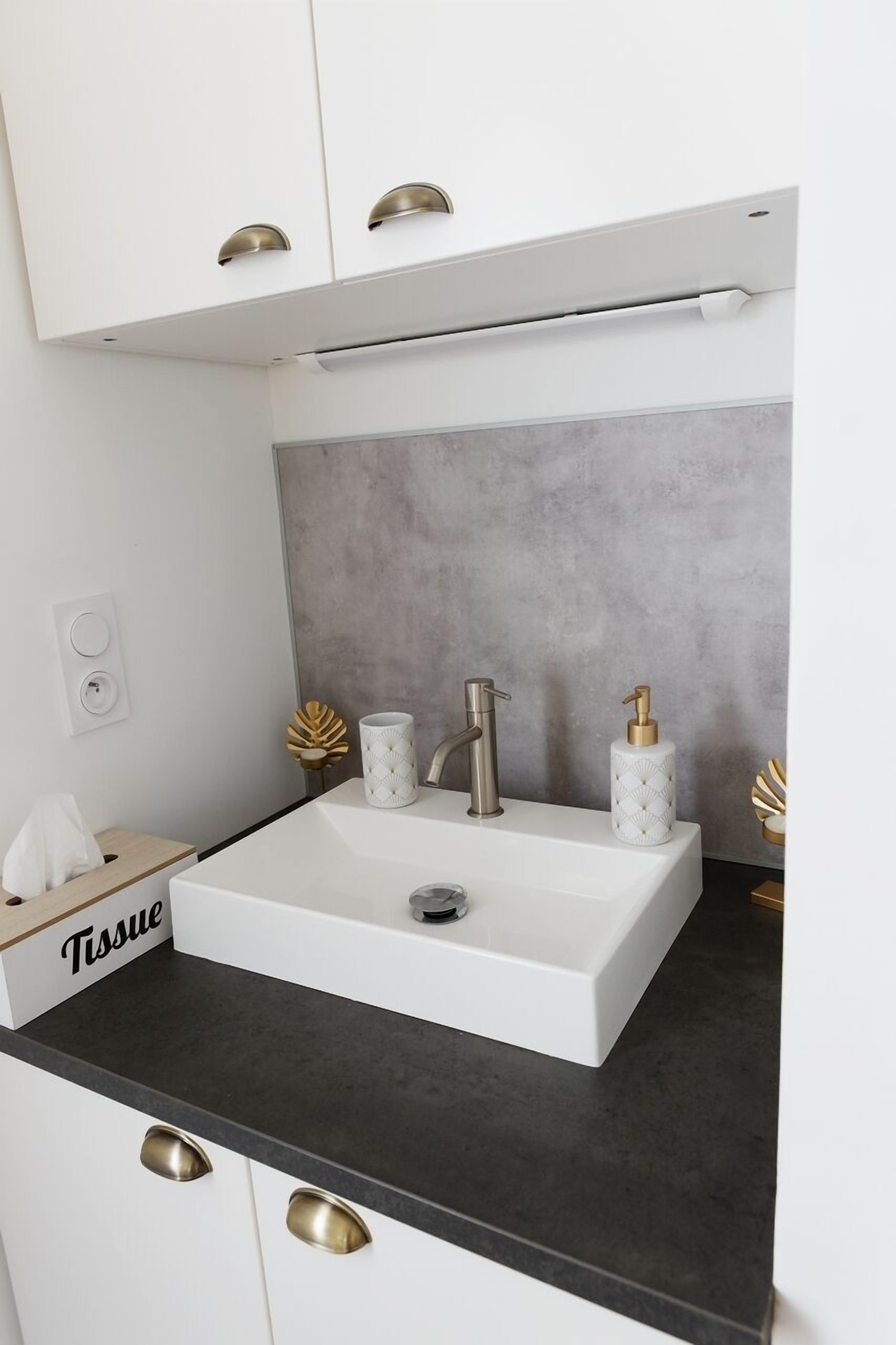 A modern kitchen with a white sink, black countertop, and gold handles.