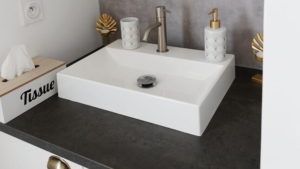 A modern kitchen with a white sink, black countertop, and gold handles. - Le Cocon de Lily (Saint-Savin)
