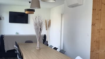 Un espace repas moderne avec une table en bois, des chaises grises et des luminaires suspendus.