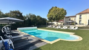 A backyard with a swimming pool, surrounded by artificial grass, lounge chairs, and umbrellas. - Charming gîte "Chez Erwann" 108m2 (Saint-Just)