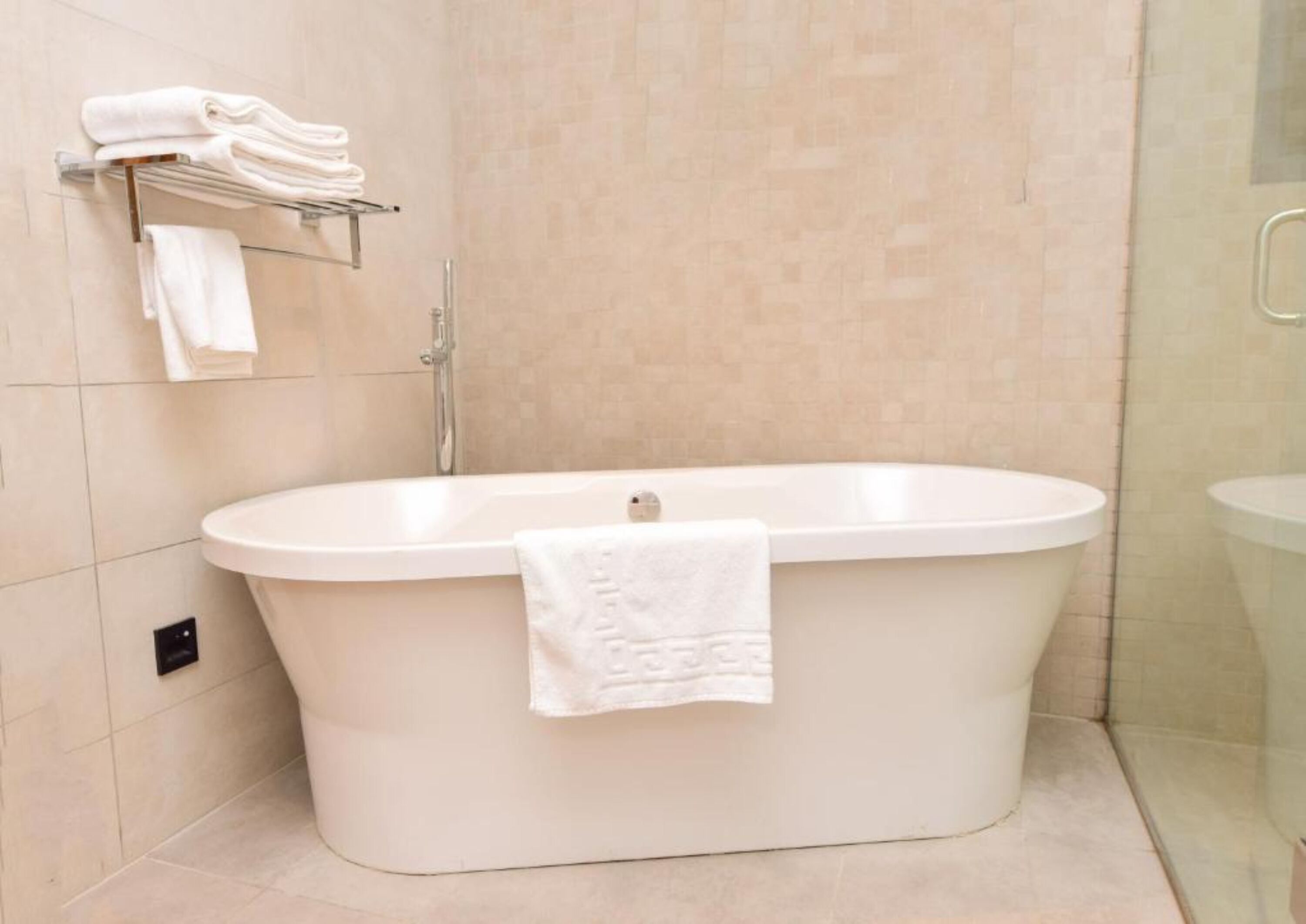 Une salle de bain moderne avec une baignoire sur pieds, une douche en verre et un porte-serviettes avec des serviettes pliées.