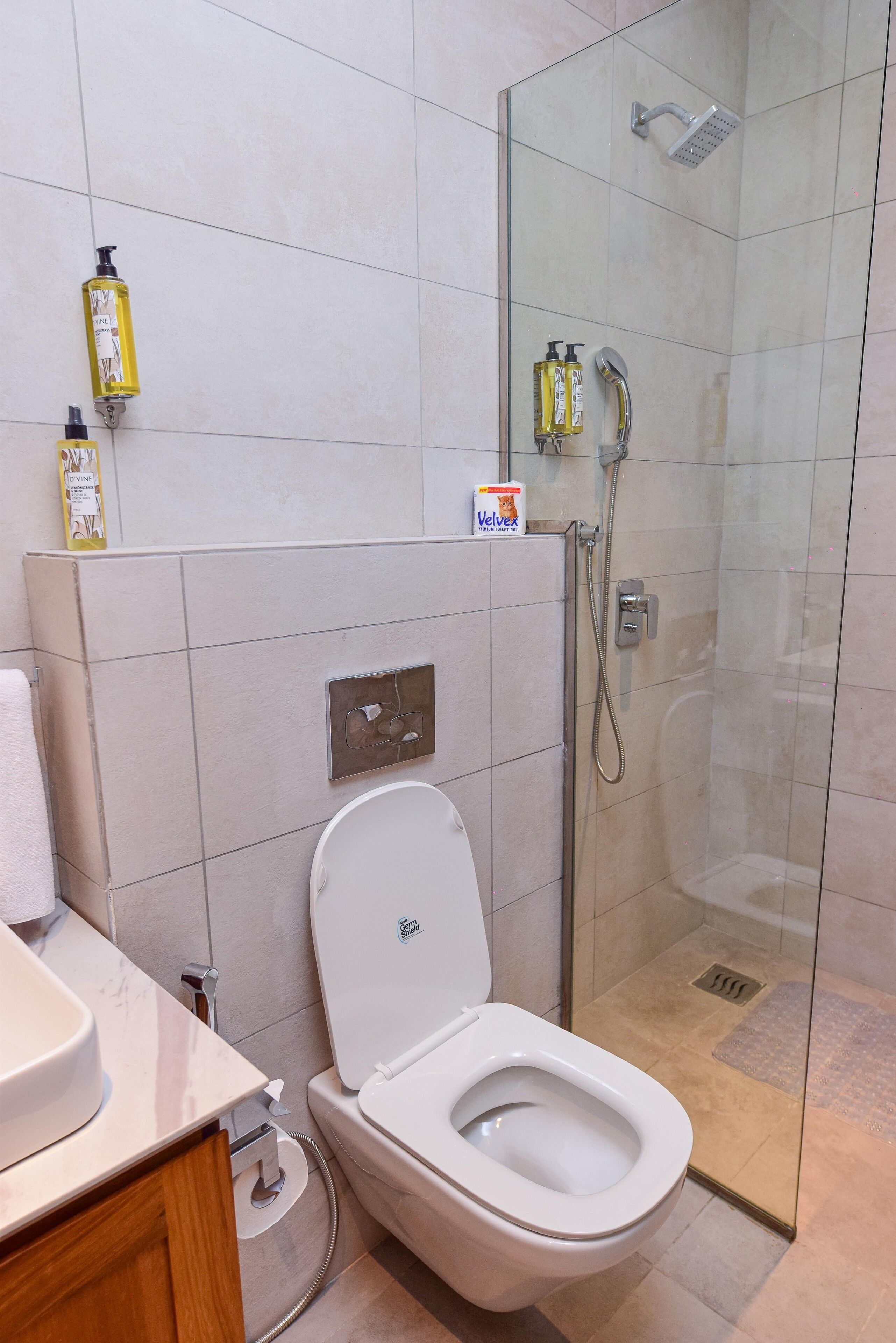 Un baño moderno con inodoro, ducha y artículos de aseo en la pared.