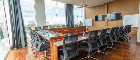 A conference room with a long table, black chairs, and a whiteboard.