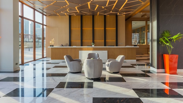 A modern lobby with a check-in counter, seating area, and large windows.