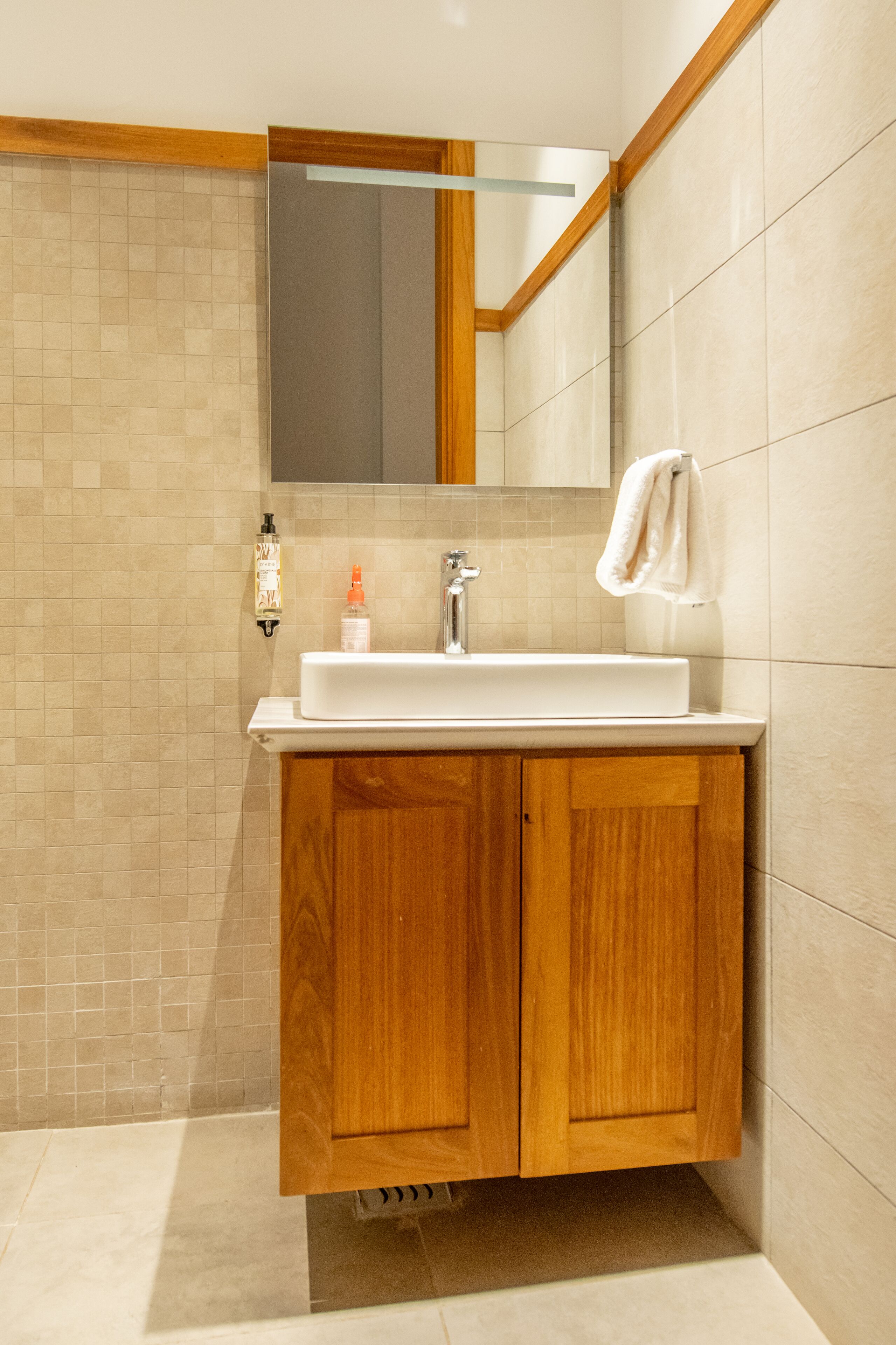 Une salle de bain avec un meuble-lavabo en bois, un lavabo blanc et un miroir au-dessus.