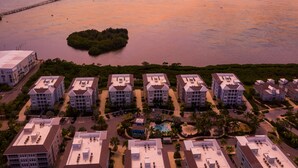 A coastal hotel with multiple buildings, a central swimming pool, and a dock extending into the water. - Turquoise Turtle One Particular Harbour 388-403 · Sound Views · 14-Night Min (Bradenton)