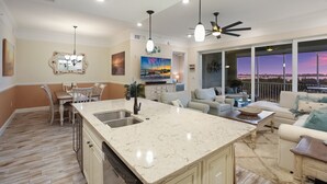 A spacious living area with a large island, a dining area, and a balcony with a scenic view. - Turquoise Turtle One Particular Harbour 388-403 · Sound Views · 14-Night Min (Bradenton)
