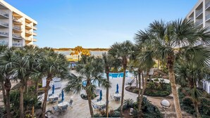 Un resort con zona de piscina rodeada de palmeras y sillones de descanso.