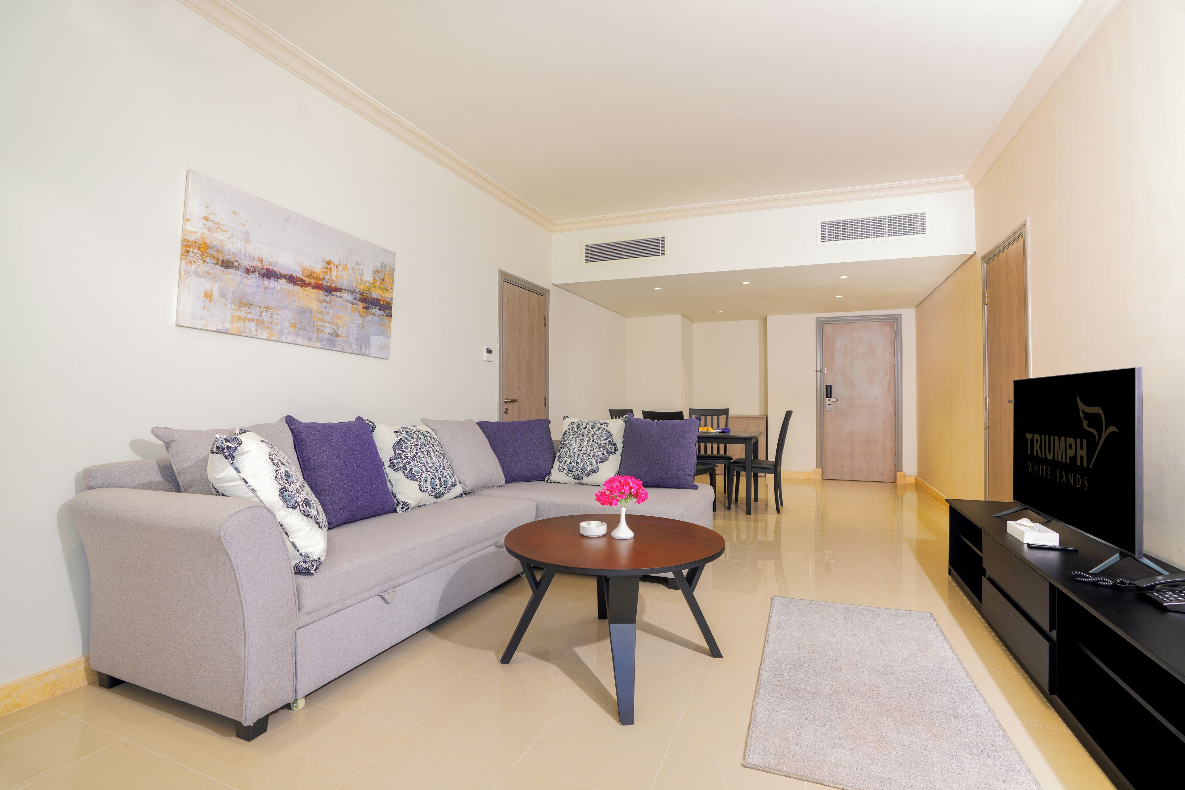 Ein modernes Wohnzimmer mit einem grauen Sofa, einem Couchtisch und einem Flachbildfernseher.