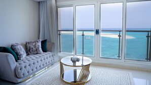 Ein modernes Wohnzimmer mit einer Couch, einem runden Couchtisch und großen Fenstern mit Blick auf einen Strand.