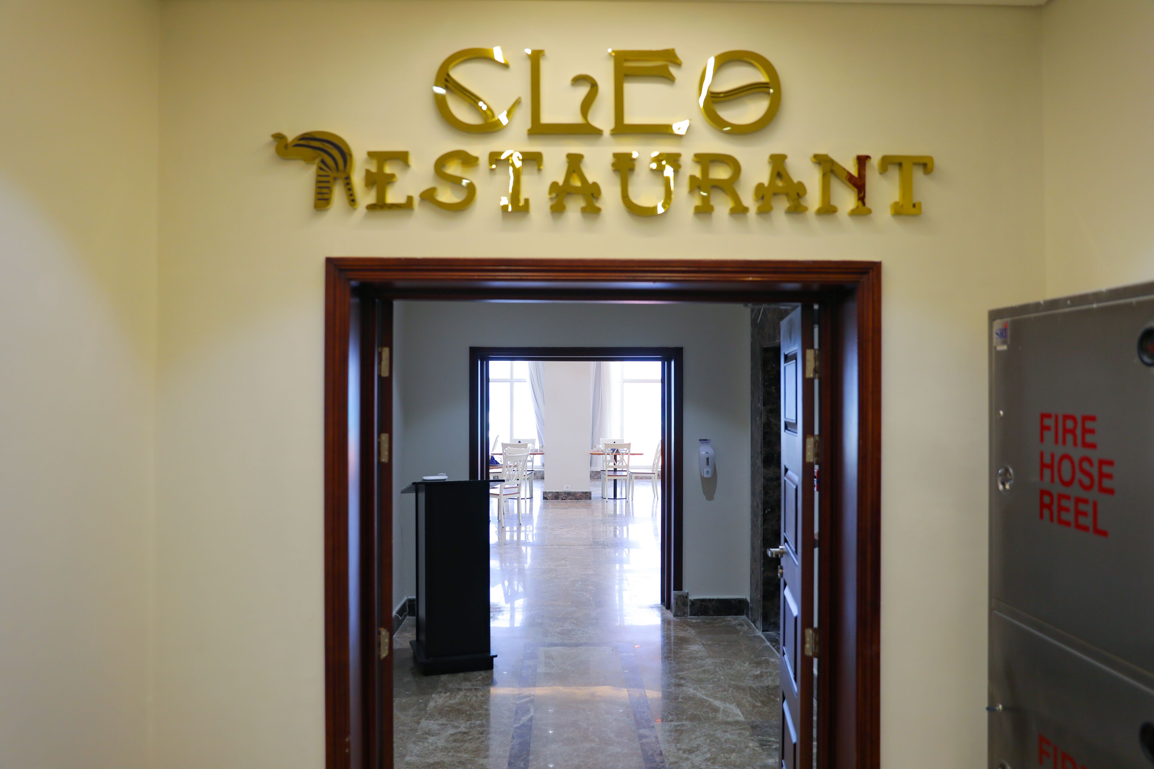 A hallway leading to a restaurant with a sign reading "CLEO RESTAURANT".