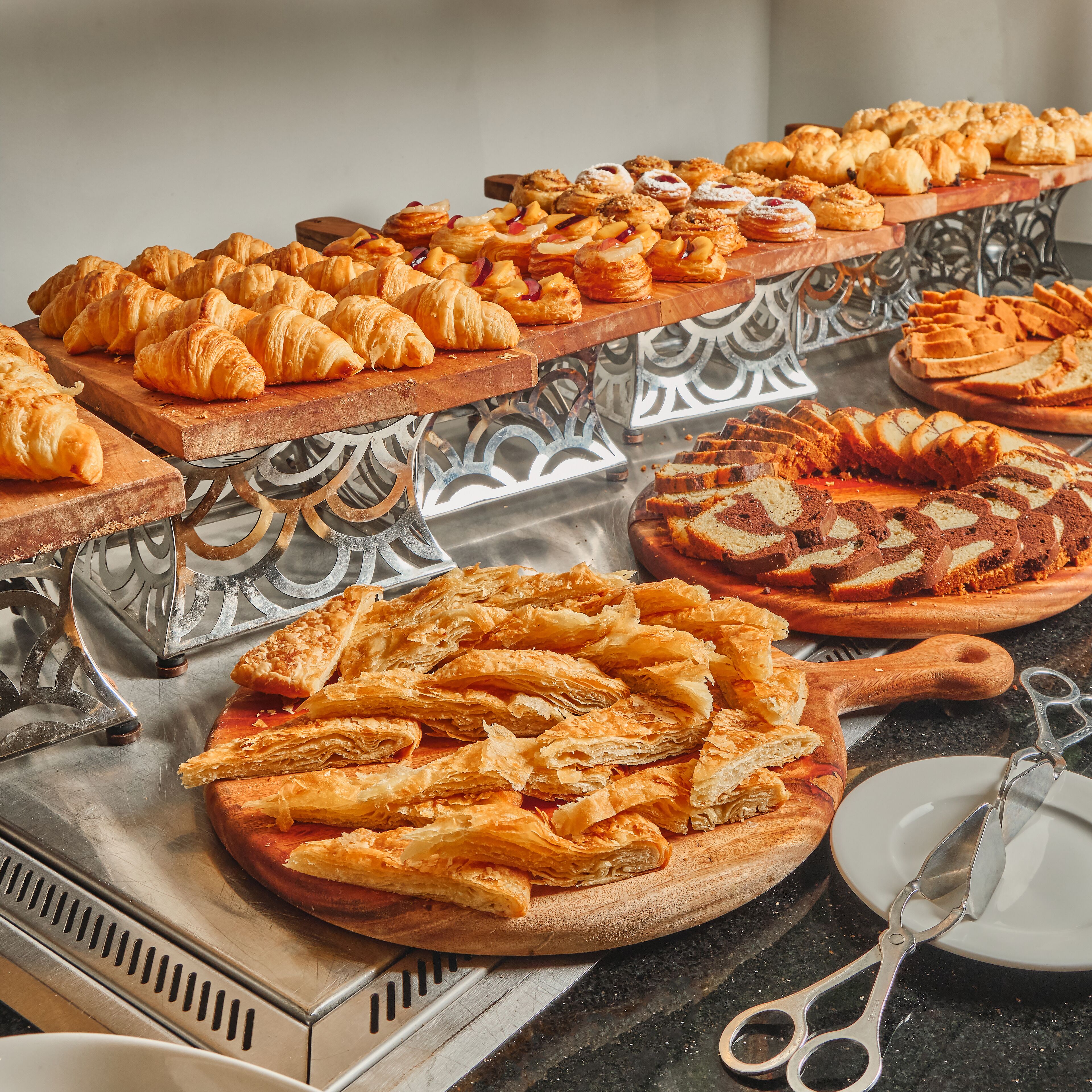 Un bufé con diversas opciones de panadería, incluyendo cruasanes, pasteles y tartas.