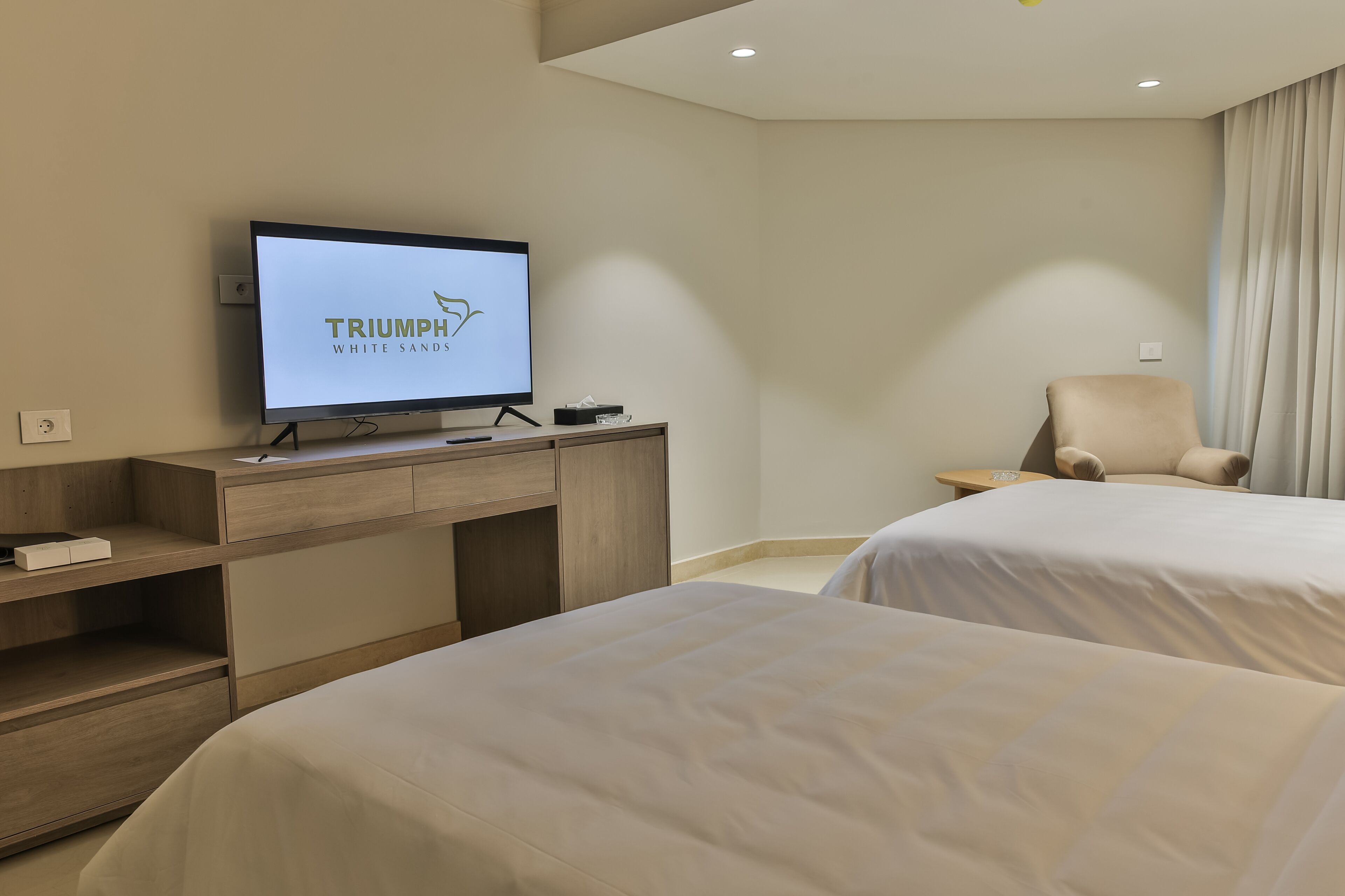 A hotel room with a bed, a chair, a TV, and a desk.