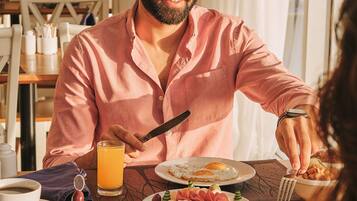 A breakfast setting with a variety of dishes including eggs, meats, and vegetables, and a person using a fork.