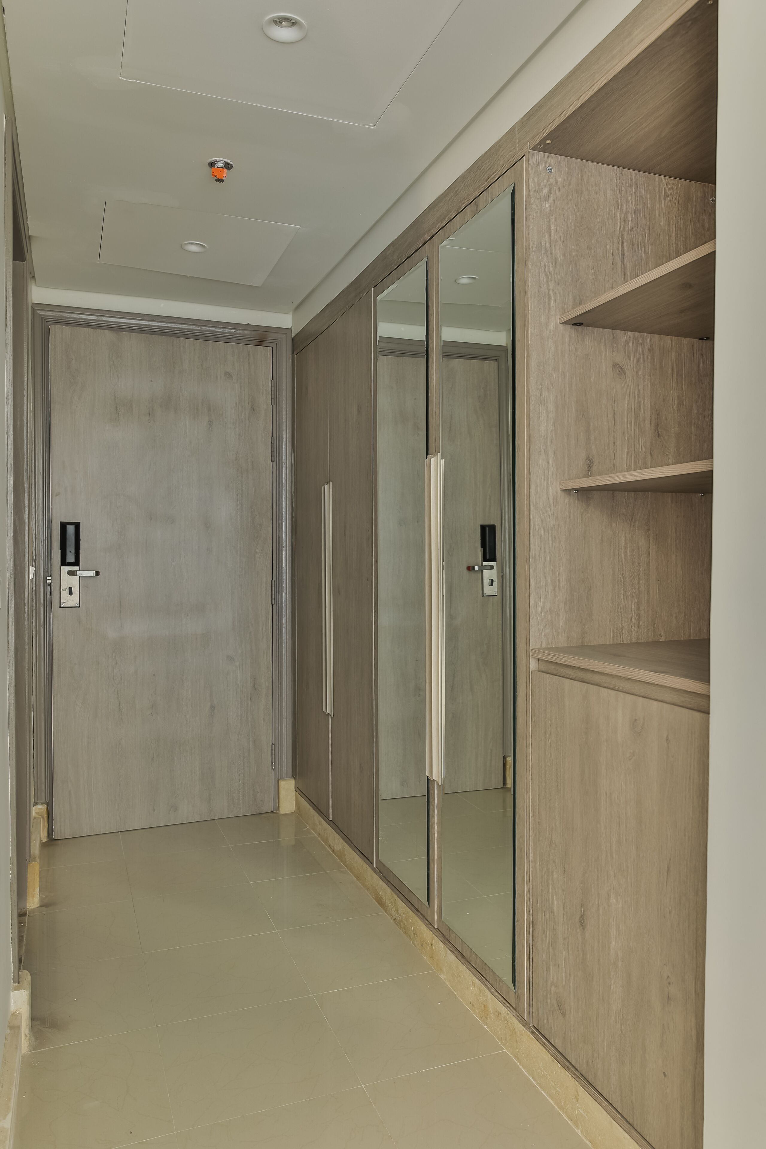 A hallway with a wooden wardrobe, a door with a handle, and a light fixture on the ceiling.