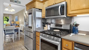 Enjoy cooking in this well-equipped kitchen with a refrigerator, microwave, and gas stove, and dine at the adjacent table.