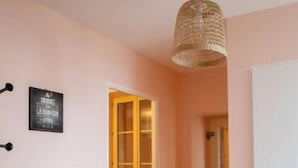 Un pasillo con una mesa de madera, una lámpara de fibra y una puerta que da a otra habitación.