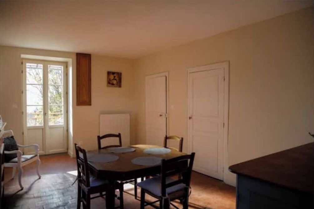 A dining area with a table and chairs, a window with a view, and a door.