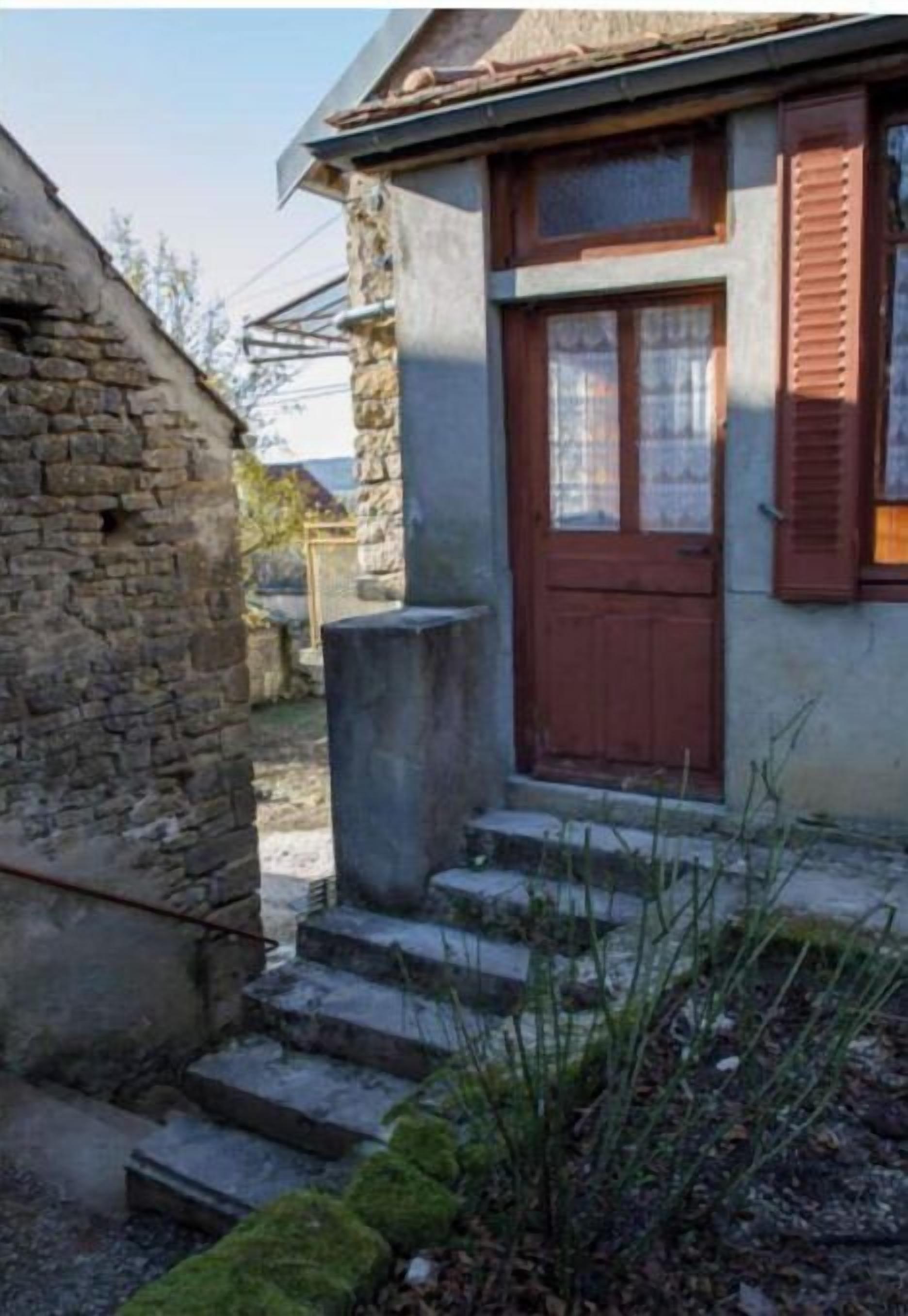 A stone building with a wooden door and steps leading to a porch.