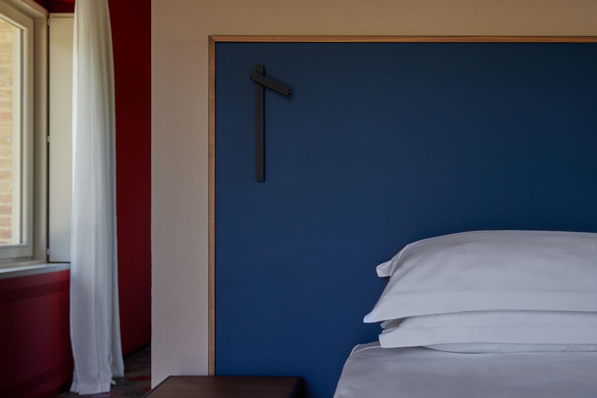 A room with a bed, a window with curtains, and a door with a cross on it.