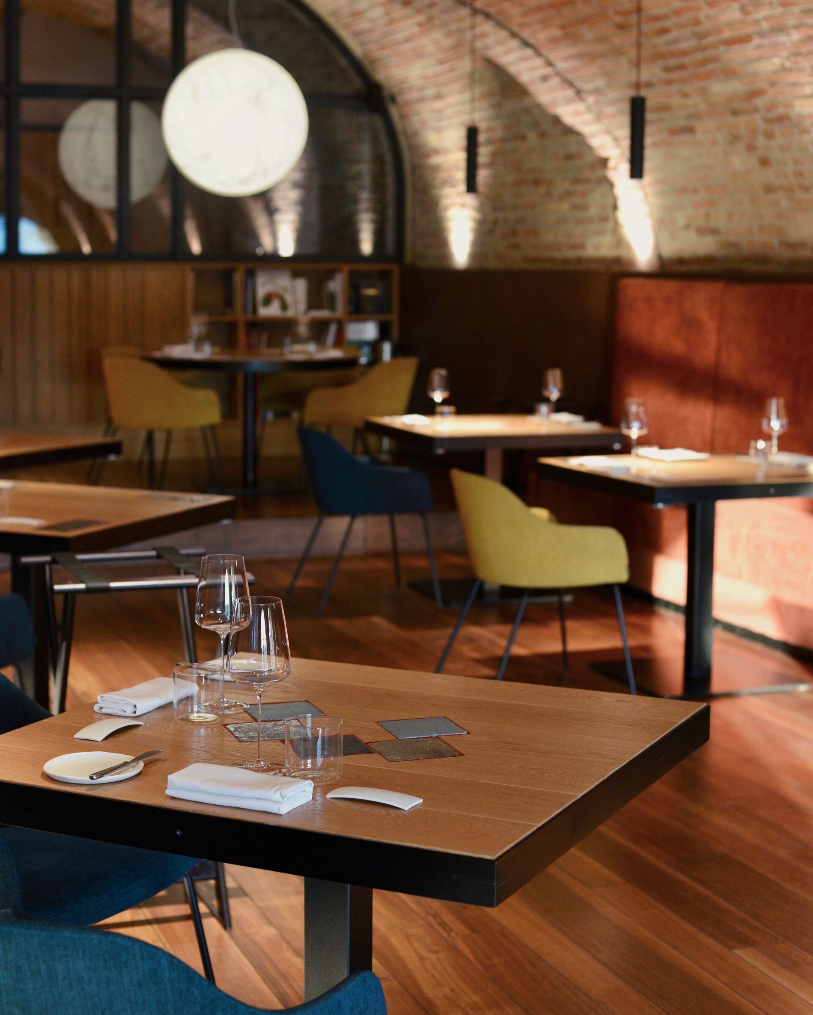 Ein Restaurantinnenraum mit Holztischen, Stühlen und einer Ziegelwand.