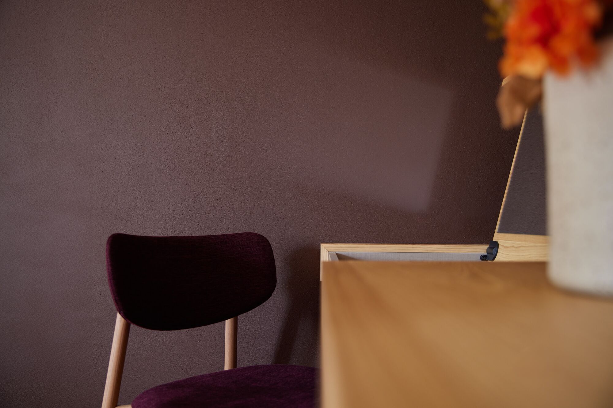 Une chaise avec un coussin foncé et un bureau en bois dont le plateau est de couleur claire.