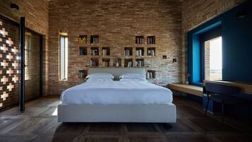 Ein Schlafzimmer mit Ziegelwand, einem großen Bett und Bücherregalen.