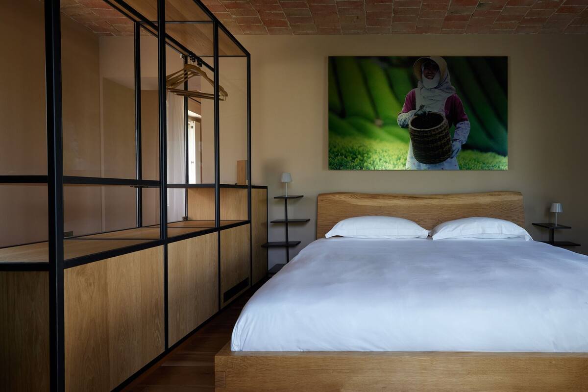 Une chambre à coucher avec un lit en bois, une armoire intégrée et un tableau accroché au mur représentant une personne tenant un panier.