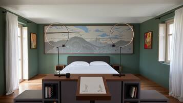 A bedroom with a bed, two bedside tables, a large artwork above the bed, and a desk with a chair in the center.