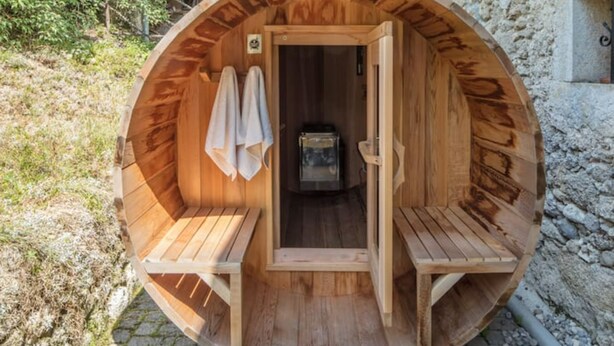 A wooden sauna with two benches and a door leading to a small room with a heater. - Artist'au Chat" family gîte with sauna (saint paul)