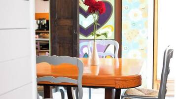 A dining area with a wooden table, two chairs, and a vase with red flowers.