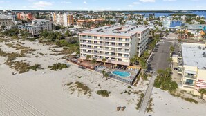 Ein Strandhotel mit mehreren Balkonen, einem Swimmingpool und einem Parkplatz.
