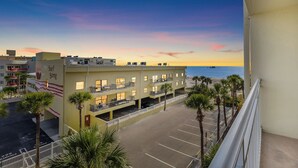 Ein Hotel mit Parkplatz, mehreren Etagen und Blick auf den Strand und das Meer bei Sonnenuntergang.