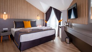 A modern hotel room with a large bed, wooden panel walls, a flat-screen TV, and a small kitchenette. - Saint Star Kemer (Kemer)