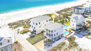 Una propiedad frente a la playa con varias edificaciones, una piscina y vistas a la playa.