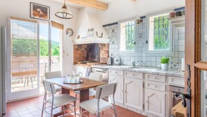 Eine Küche mit weißen Schränken, einem Backofen aus Ziegelsteinen und einem Essbereich mit Tisch und Stühlen.