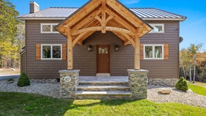 A two-story house with a wooden porch, stone steps, and a brown door. - 5BR Retreat w/ Hot Tub - Sleeps 12 in Stratton (Stratton)
